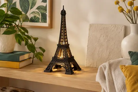 Maquette 3D noire de la Tour Eiffel en bois, assemblée et éclairée sur une table en intérieur.